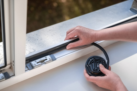 Handwerker baut eine Fensterdichtung ein