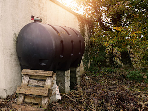 Ein alter Öltank steht auf Holzbalken.