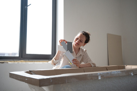 Das Bild zeigt eine Frau, die mithilfe einer Farbpalette, die passende Farbe für eine Badewanne aussucht.