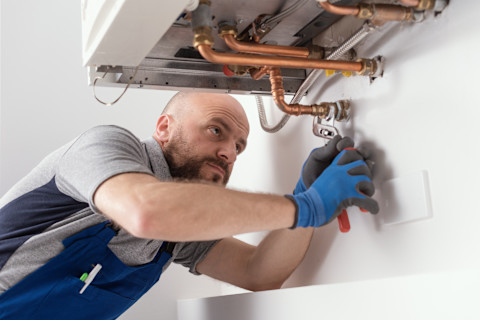 Das Bild zeigt einen professionellen Heizungstechniker bei der Installation einer Gasheizung.