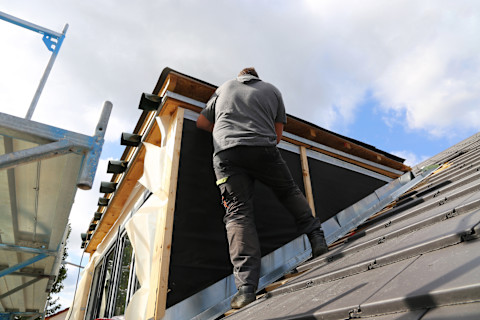 Das Bild zeigt einen professionellen Dachdecker beim Einbau einer Dachgaube.