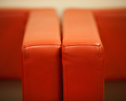 Das Bild zeigt ein Sofa, das auf einer Seite ein altes, und auf der anderen Seite ein neues Polster hat.