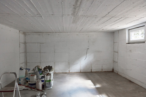 Das Bild zeigt einen Keller unter Konstruktion, mit mehreren Baumaterialien und Werkzeugen im Vordergrund.